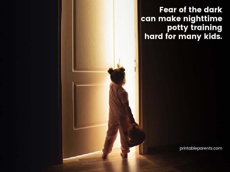 image reads 'fear of the dark can make nighttime potty training hard for many kids' with a little girl holding a teddy bear peering into a door at night