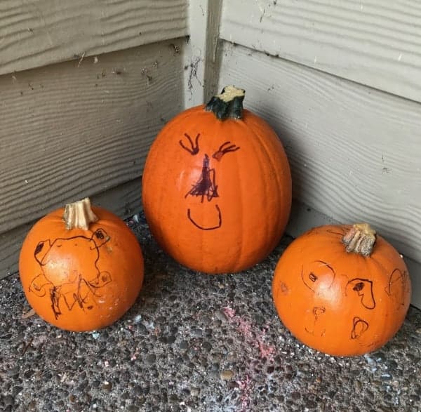 Three small pumpkins decorated with sharpies