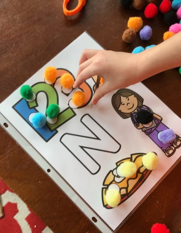 beginning sound worksheet for letter N mat with pom poms and child with tweezers