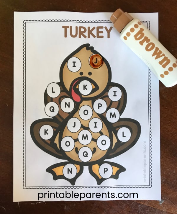 a white worksheet with a turkey clip art in full color. There are dots on the turkey with capital letters inside and brown Do a Dot Marker next to the Thanksgiving Dot page